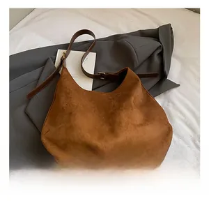 Detail of matte brown suede hobo bag with adjustable leather strap on fabric