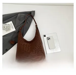 Detail of leopard print hobo bag with urban logo on textured faux leather surface