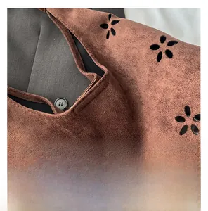 Close-up of brown suede tote bag featuring intricate laser-cut floral patterns