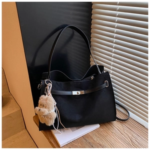 Detail of black matte tote bag with silver metal twist lock and cute plush bear charm
