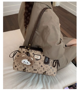 Detail of a large tote bag with BC prints and a cute plush bear charm on a model