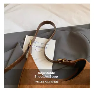 Close-up of adjustable leather strap and vintage metal buckle on brown suede tote bag