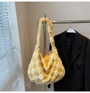 Detail of yellow plush checkerboard tote bag with soft texture hanging on a metal hanger