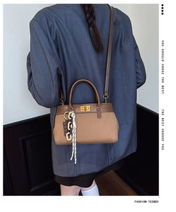 Sac seau chic en cuir marron avec fermoir doré et chaîne porté par un mannequin
