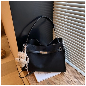 Close-up of black matte tote bag with metal twist lock and cute plush bear charm