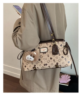 Detail of vintage beige tote bag with bear charm worn by a model in a trench coat