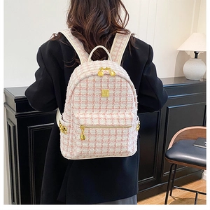 Detail of pink and beige tweed backpack with gold accents on female model in warm setting