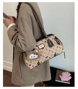 Detail of beige tote bag with bear pattern, drawstring sides and plush bear charm