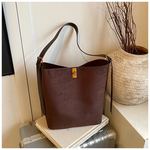 Detail of a dark brown suede bucket bag featuring a polished gold rectangular metal buckle
