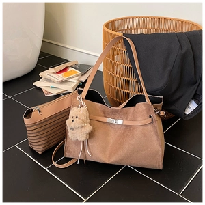 Detail of vintage brown suede tote bag with metal twist lock and cute plush puppy charm