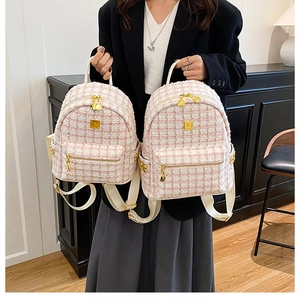 Detail of pink and white tweed backpack featuring gold-tone zippers and polished hardware