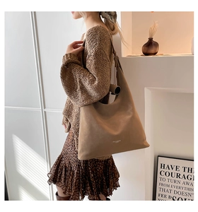 Close-up of large brown tote bag with matte leather texture and white logo