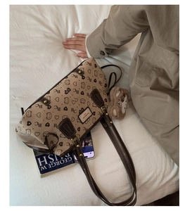 Detail of retro tote bag with heart patterns and cute plush bear charm on white bedsheet