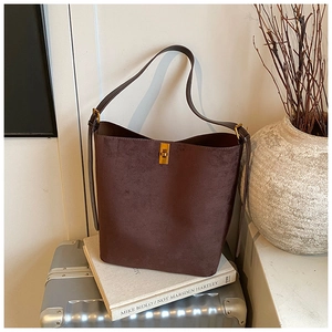 Detail of dark brown suede bucket bag featuring a premium gold metallic twist-lock closure