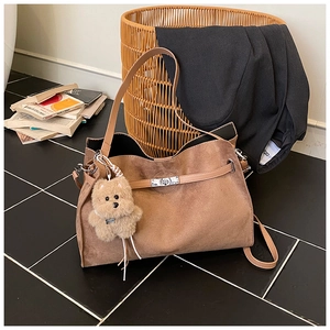 Detail of vintage brown suede tote bag featuring silver twist lock and puppy pendant
