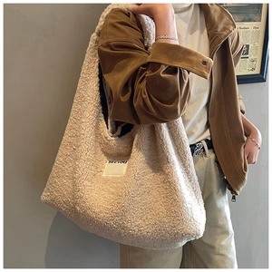 Close-up of soft beige faux shearling hobo tote bag featuring a stitched logo label