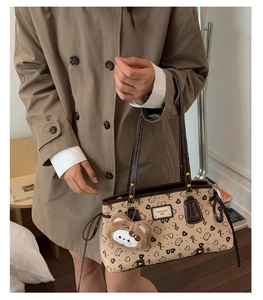 Detail of khaki tote bag with plush bear charm and heart pattern on canvas