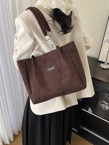 Sac cabas en daim marron avec bandoulière chaîne porté par un mannequin dans un intérieur