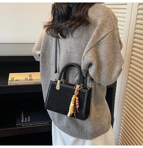 Détail du sac bandoulière en suédine avec poignée tressée et pompon en perles colorées
