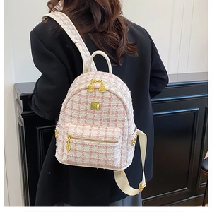 Close-up of pink tweed backpack with white leather straps on a dark suit background