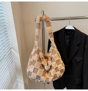 Detail view of khaki plush checkerboard shoulder bag hanging on a metal hanger