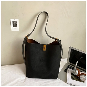 Detail of black suede bucket bag with gold buckle and adjustable strap in office setting