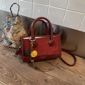 Detail der burgunderroten Vintage-Umhängetasche mit mattem Wildleder und glänzendem Lackleder