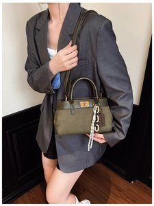 Détail du sac à main en toile vert olive avec boucle en métal rétro et breloques décoratives