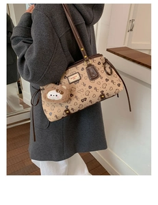 Detailed view of cream tote bag with bear print, heart patterns and brown plush charm