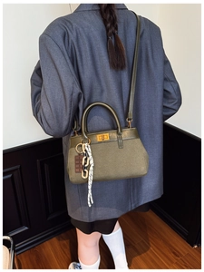 Detail of olive green bucket bag with gold twist lock and woven chain accessory