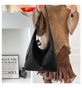 Detail shot of black hobo tote bag with matte texture and brand logo for winter fashion