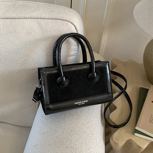 Nahaufnahme der schwarzen matten Ledertasche mit glattem Rand auf strukturiertem Sofa