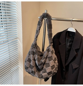 Detail of grey checkered plush shoulder bag hanging on a hanger with a black suit jacket