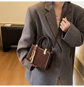 Détail du sac bandoulière en daim marron avec poignée tressée et perles ethniques