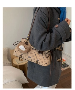 Detail of cute cat pattern print on beige shoulder bag with brown plush animal charm
