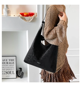 Close-up of black suede hobo tote bag with a minimalist shoulder strap design