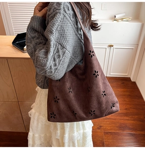 Detail of laser-cut floral pattern on dark brown faux suede tote bag with long shoulder strap