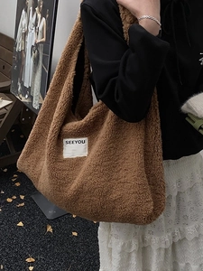 Large brown fuzzy tote bag with SEEYOU label worn with casual outfit on street