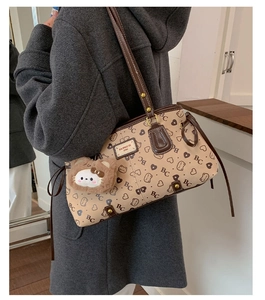 Detail of vintage beige tote bag featuring heart patterns and soft cat plush pendant