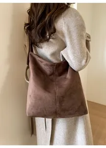 Detail view of large brown frosted suede shoulder bag on model with wool coat