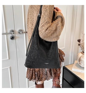 Detail of black suede hobo bag with adjustable strap and white logo for daily commute