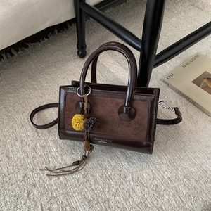 Detail der vintage dunkelbraunen Umhängetasche mit mattem Finish und Bommel-Anhänger