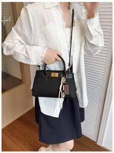 Détail du sac seau noir avec fermoir en métal doré et pendentif en corde tressée