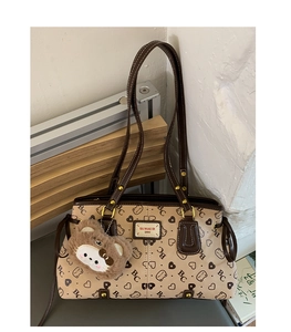 Detail of retro beige tote bag featuring letter print and cute cat plush pendant