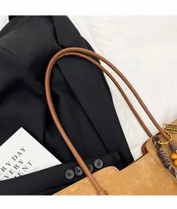 Close-up of brown tote bag straps with braided tassel and yellow bead detail