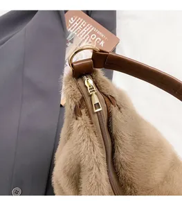Vue détaillée du zip doré et de la fourrure synthétique brune sur le sac fourre-tout