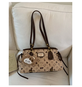 Close-up of beige leather tote with BC monogram print and plush cat keychain detail
