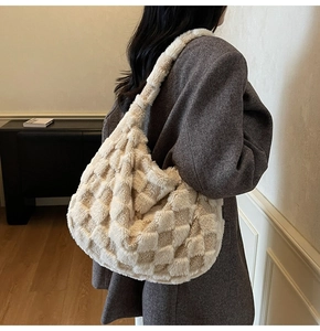 Detailed view of the soft checkerboard plush hobo bag worn by a model in a cozy room