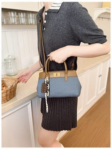 Détail du sac seau en toile bleue avec cuir marron, fermoir en métal et foulard