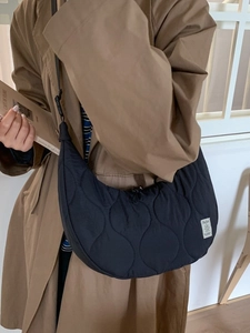 Borsa a tracolla a mezzaluna trapuntata nera da donna con trama a onde e etichetta di marca